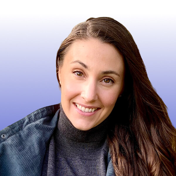 A woman with long brown hair smiles at the camera, dressed in a dark turtleneck sweater and jacket. The background is a smooth gradient from white to blue, reminiscent of the signature style seen at Gainsight Pulse events.