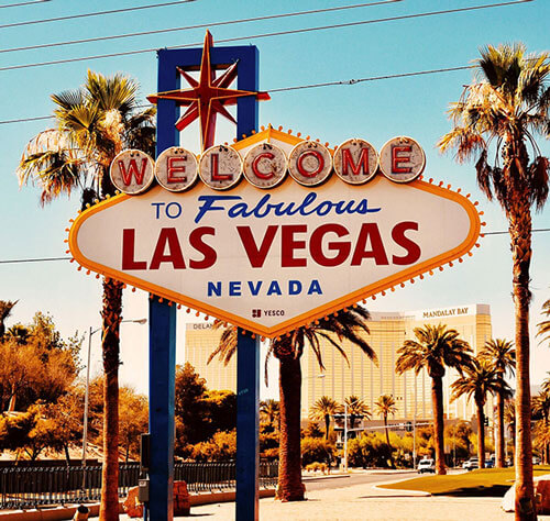 The iconic “Welcome to Fabulous Las Vegas, Nevada” sign stands surrounded by palm trees and hotels, inviting visitors to the city where events like Gainsight Pulse thrive under a clear blue sky.